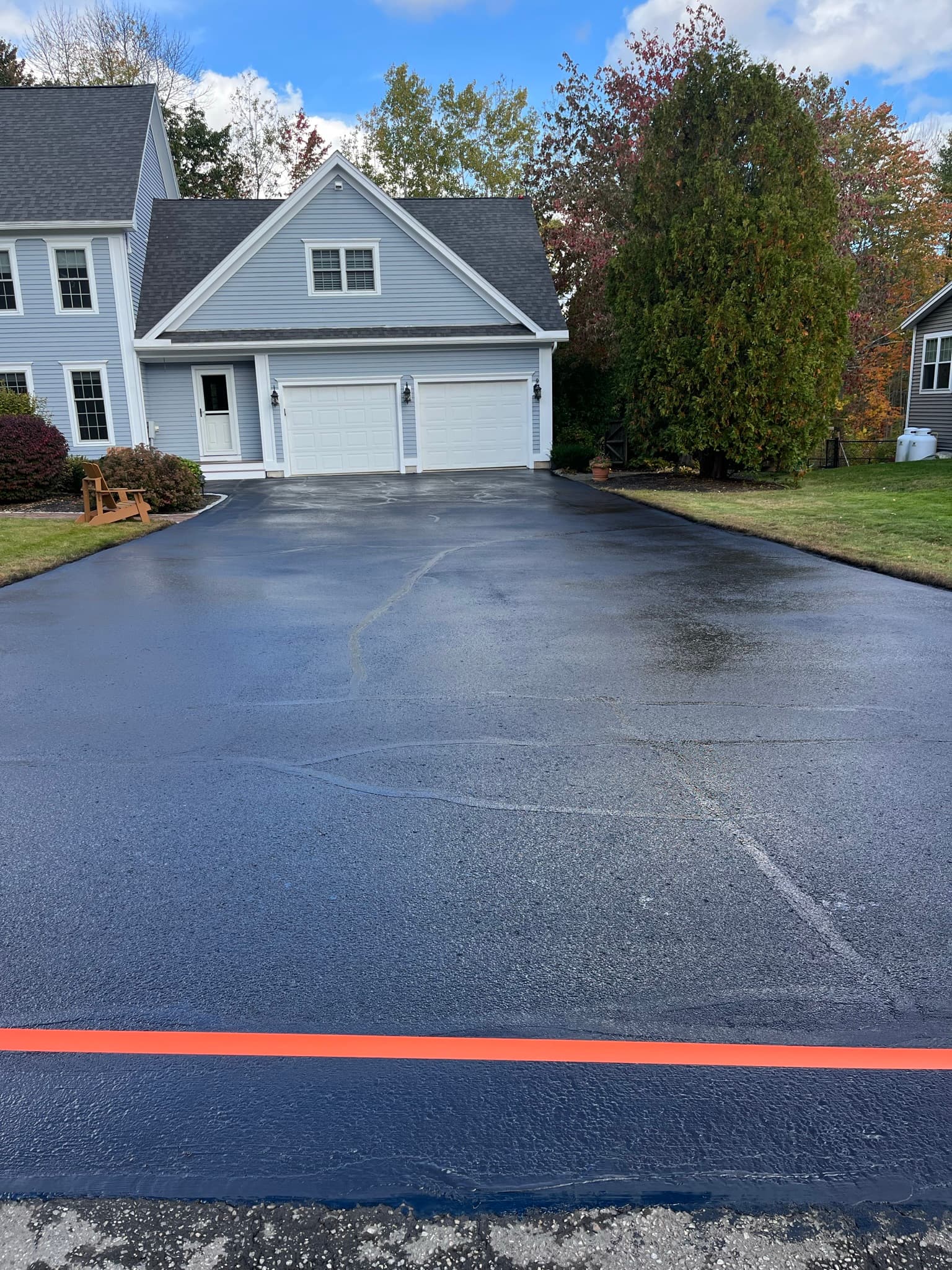Cape-style home with long straight driveway, uniform sealcoat coverage edge to edge