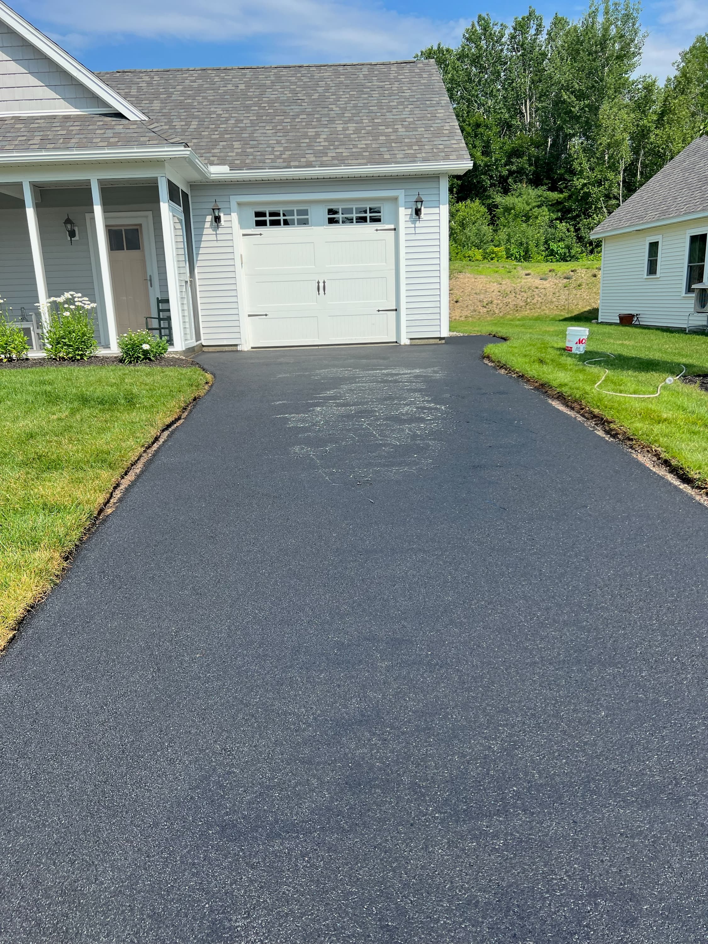 Residential driveway with garage apron, fresh sealcoat, clean edge work throughout