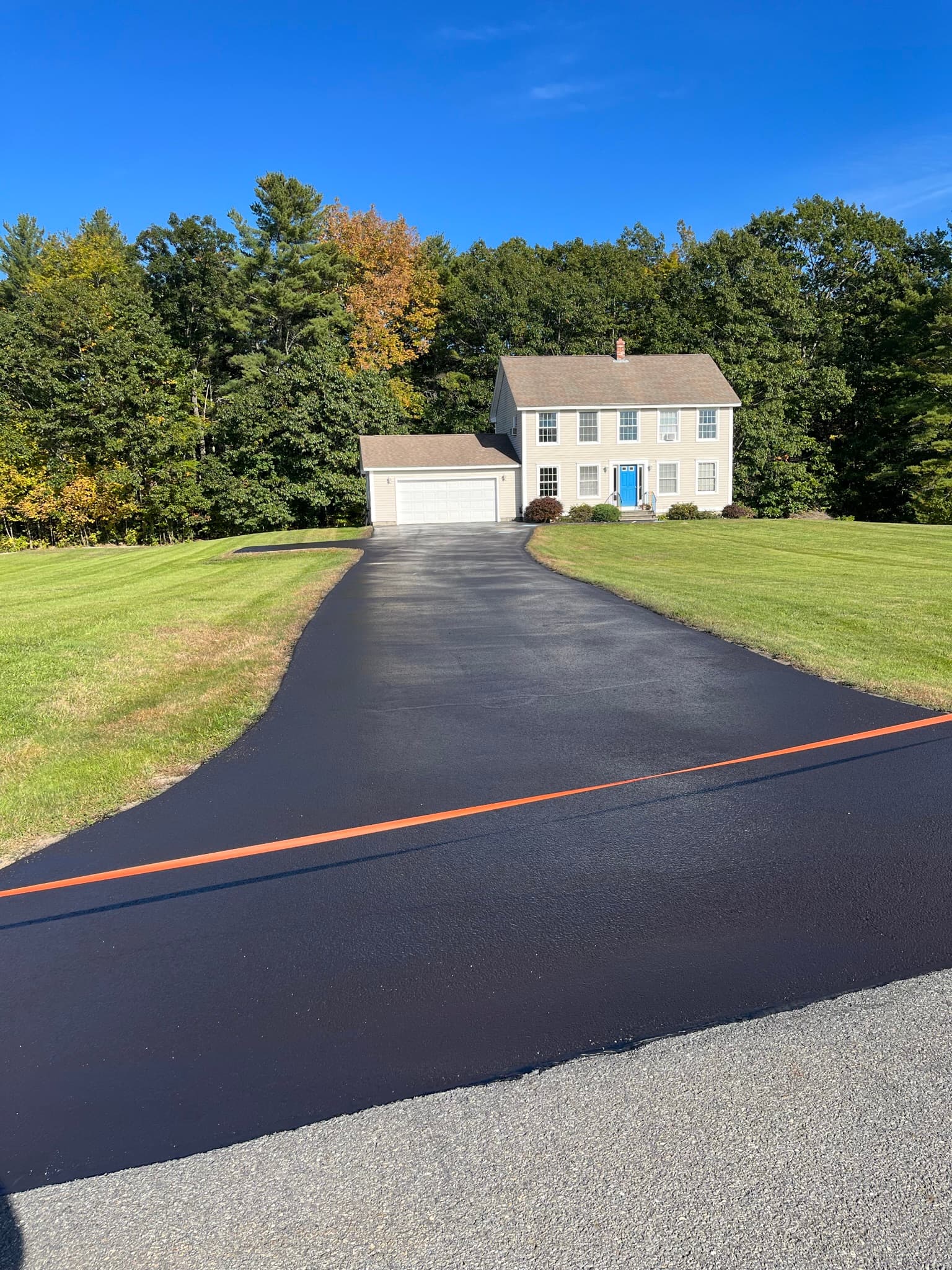 Driveway sealed and roped off with red barrier tape, curing in summer heat