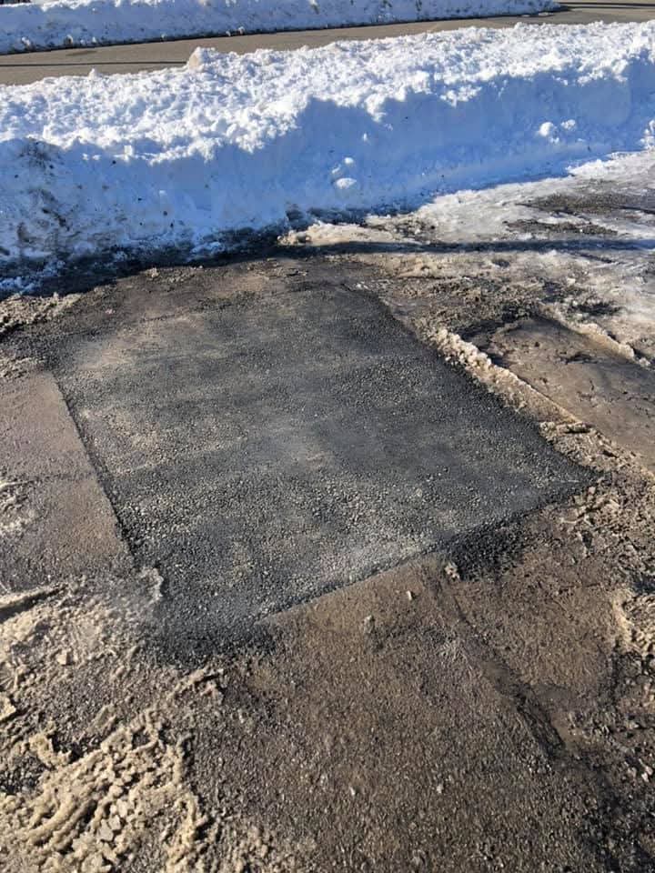 Completed square-cut asphalt patch in winter conditions, solid repair even in cold weather